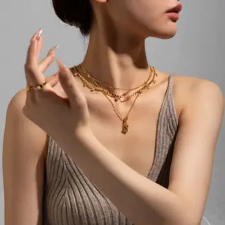 Close-up of FY’s electroplated 18K gold brass zircon stone necklace with a round lock clasp, styled over a chic neckline.