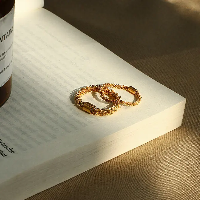 FY’s 18K PVD gold minimalist ring stacked with raw-edge bands for modern gender-neutral style.